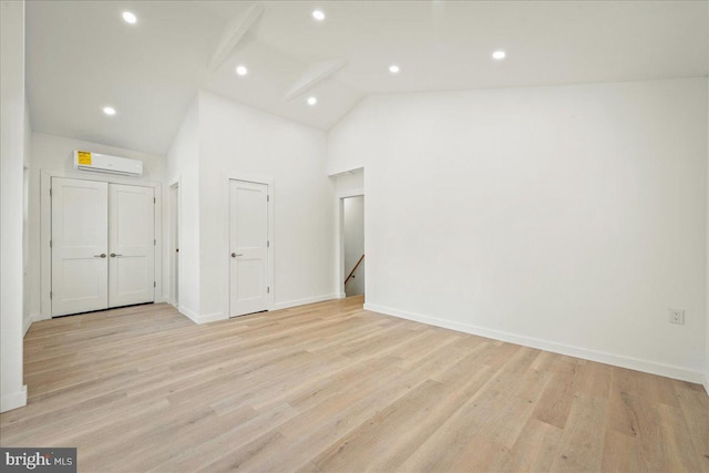 unfurnished room featuring high vaulted ceiling, recessed lighting, baseboards, light wood finished floors, and a wall mounted air conditioner