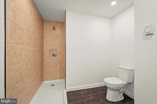 full bath with wood tiled floor, baseboards, tiled shower, and toilet