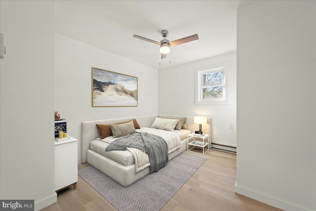 bedroom featuring light wood-style floors, a baseboard radiator, baseboards, and a ceiling fan