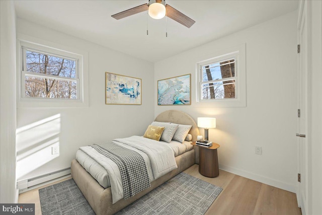 bedroom with baseboards, multiple windows, light wood finished floors, and baseboard heating