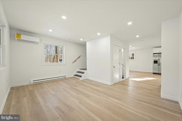 below grade area with a wall mounted AC, a baseboard radiator, light wood-style floors, stainless steel refrigerator with ice dispenser, and recessed lighting