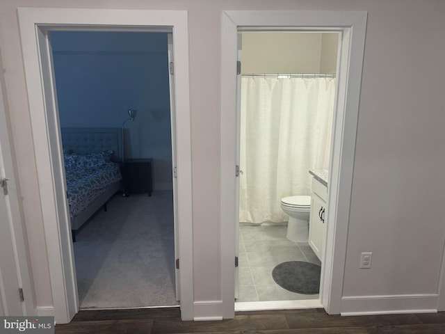 full bathroom featuring toilet, wood finished floors, vanity, baseboards, and ensuite bath