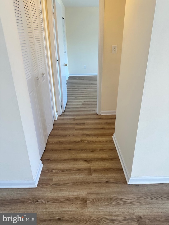 hallway featuring wood finished floors and baseboards