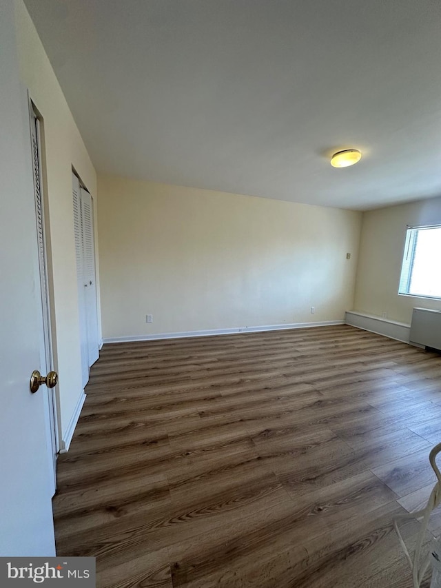 spare room with dark wood-style floors, radiator, and baseboards