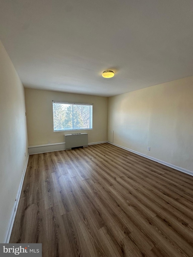 empty room featuring baseboards and dark wood-style flooring