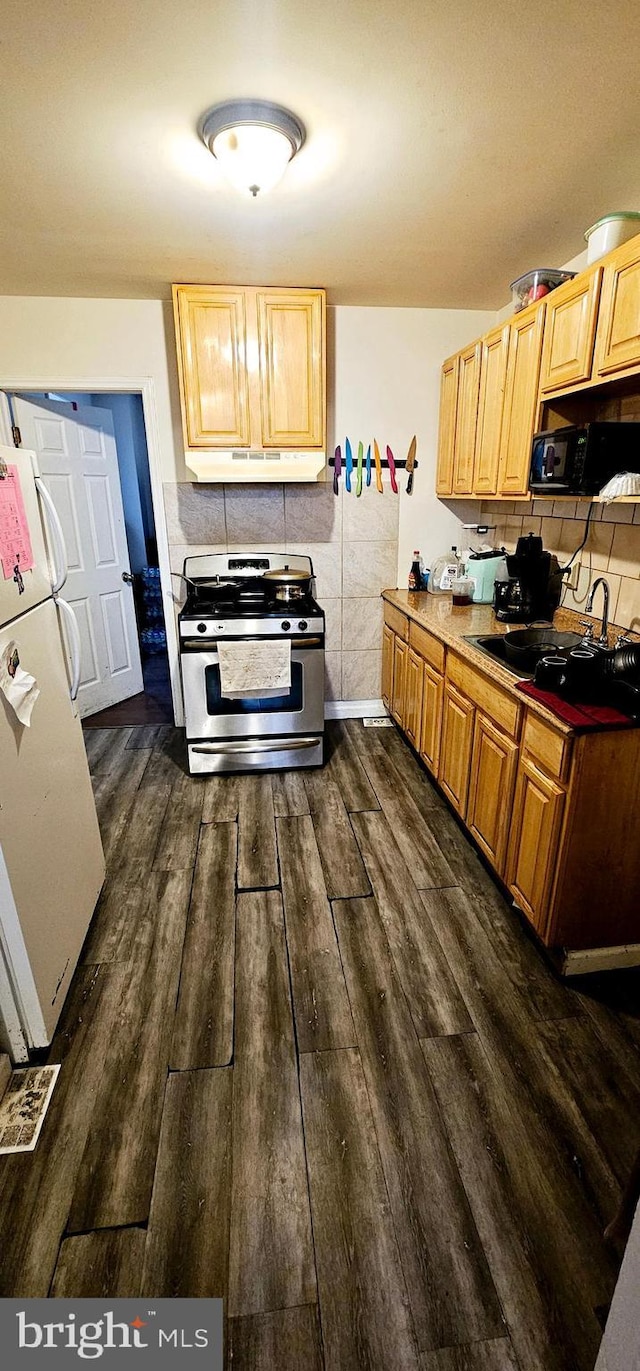 kitchen featuring stainless steel gas stove, dark wood finished floors, freestanding refrigerator, black microwave, and a sink