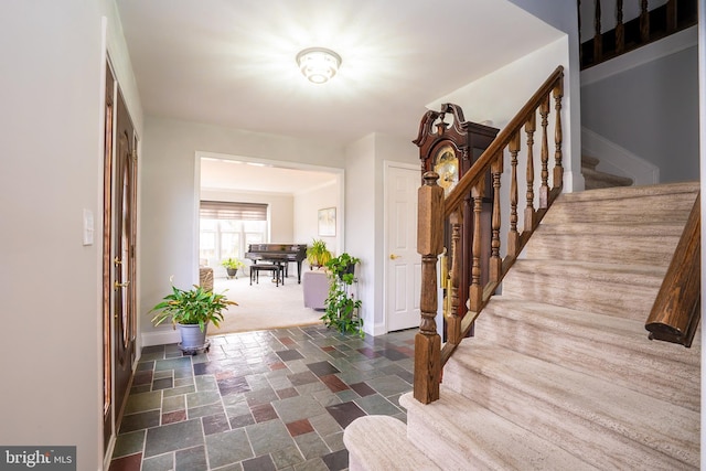 foyer with stairway, stone tile floors, and baseboards