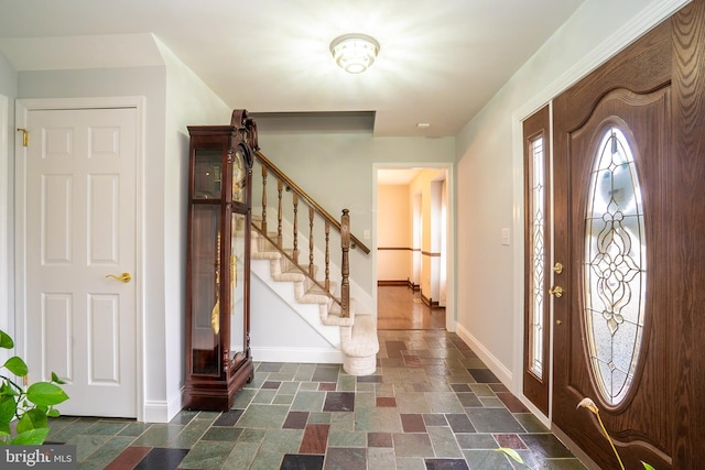 foyer featuring stairs, stone tile flooring, and baseboards