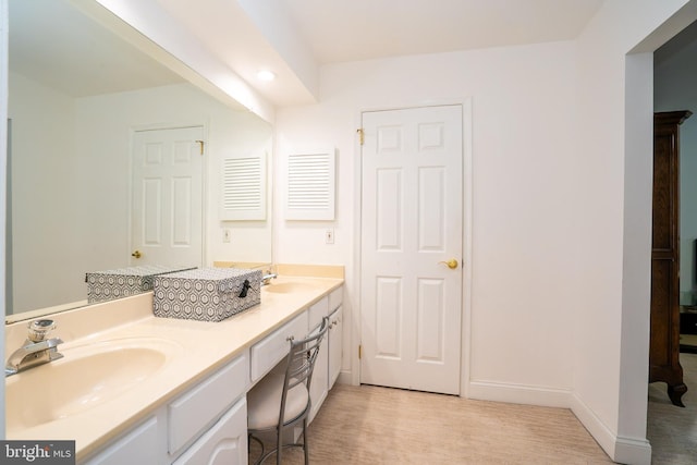 bathroom with double vanity, wood finished floors, a sink, and baseboards