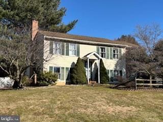 view of front of home with a chimney, fence, and a front lawn