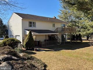 back of house featuring stucco siding, stairs, a deck, and a yard