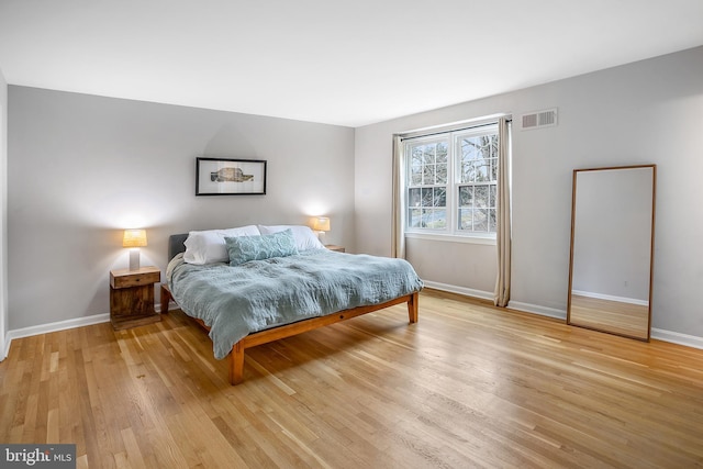 bedroom with baseboards, visible vents, and light wood finished floors