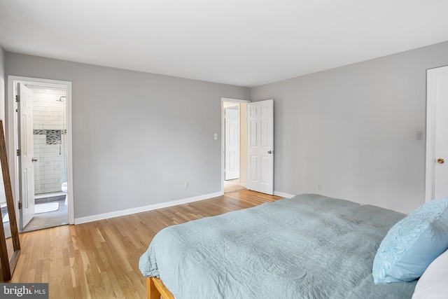 bedroom featuring connected bathroom, baseboards, and light wood-style floors