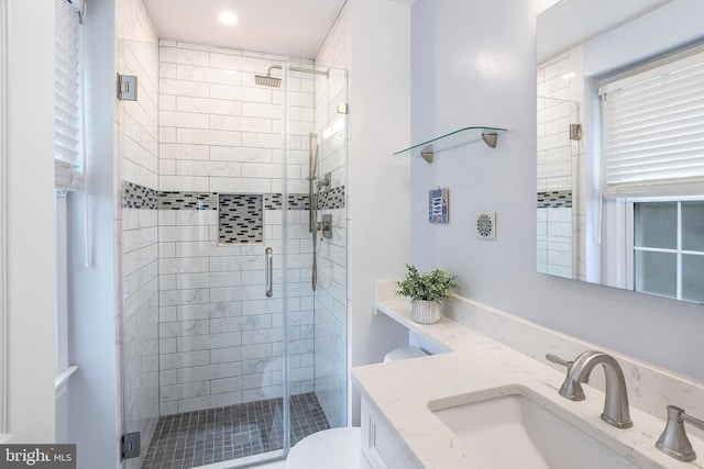 bathroom featuring toilet, a stall shower, and vanity