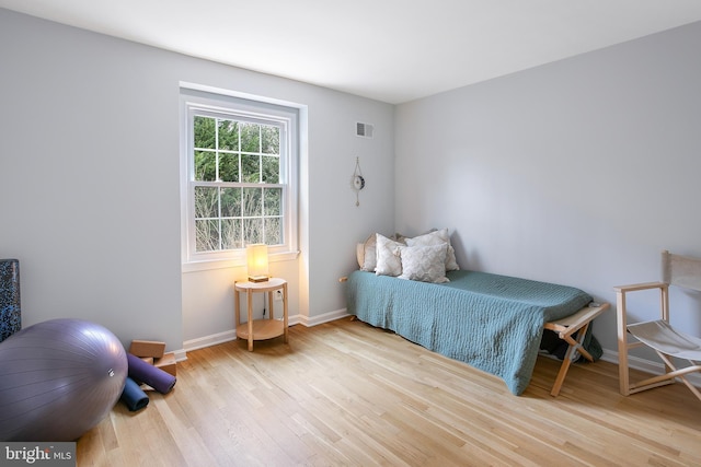 bedroom featuring wood finished floors, visible vents, and baseboards