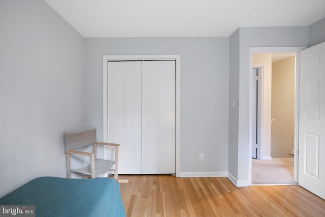 unfurnished bedroom with a closet, baseboards, and light wood-style floors