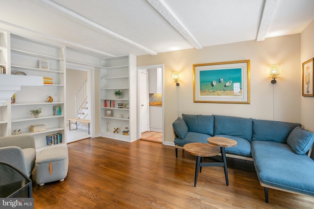 living room with beamed ceiling, baseboards, wood finished floors, and stairs