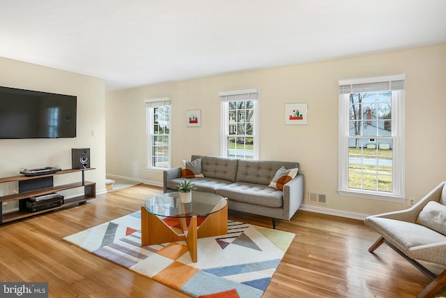 living room with visible vents, a healthy amount of sunlight, baseboards, and wood finished floors