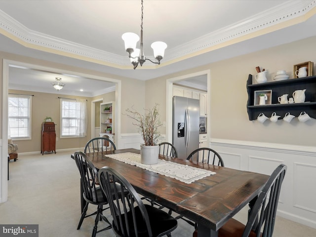 dining area with wainscoting, light colored carpet, crown molding, and a decorative wall