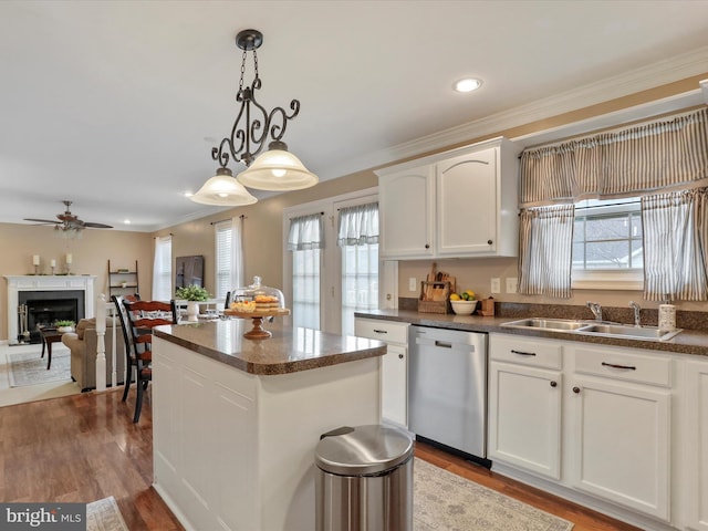 kitchen with a sink, white cabinetry, dishwasher, dark countertops, and decorative light fixtures