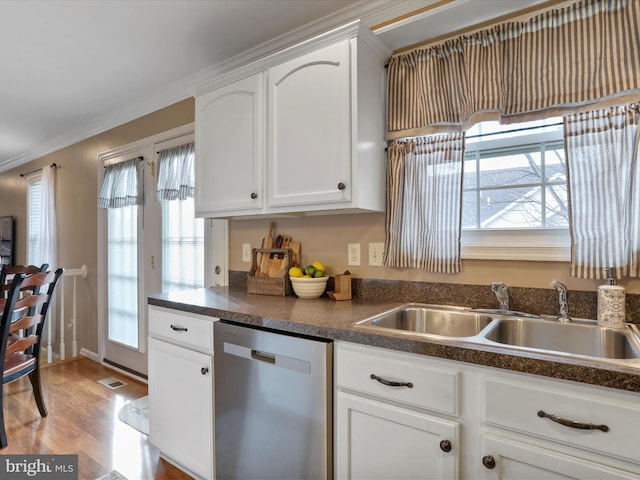 kitchen with a sink, white cabinetry, dishwasher, dark countertops, and crown molding