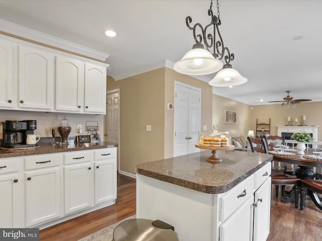 kitchen featuring white cabinets, open floor plan, decorative light fixtures, and a center island