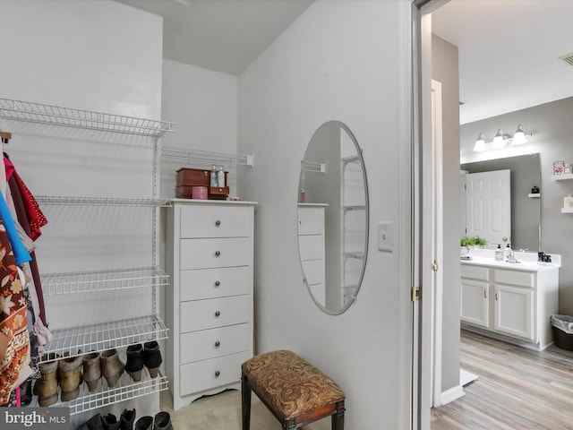 spacious closet featuring light wood-type flooring, visible vents, and a sink