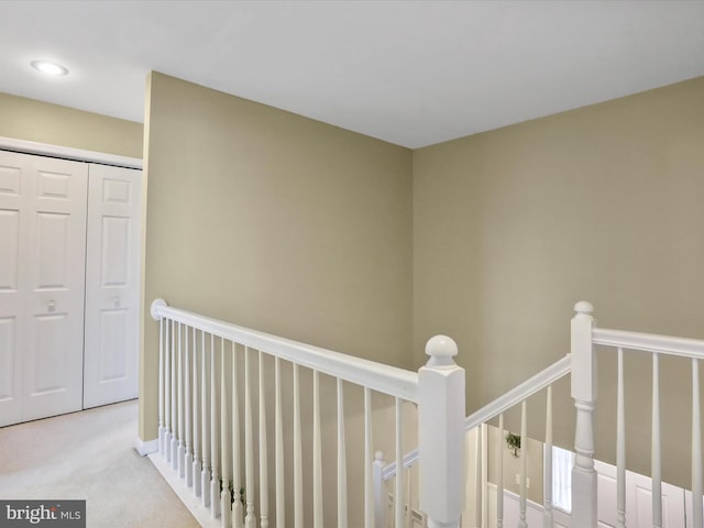 corridor featuring an upstairs landing and light colored carpet