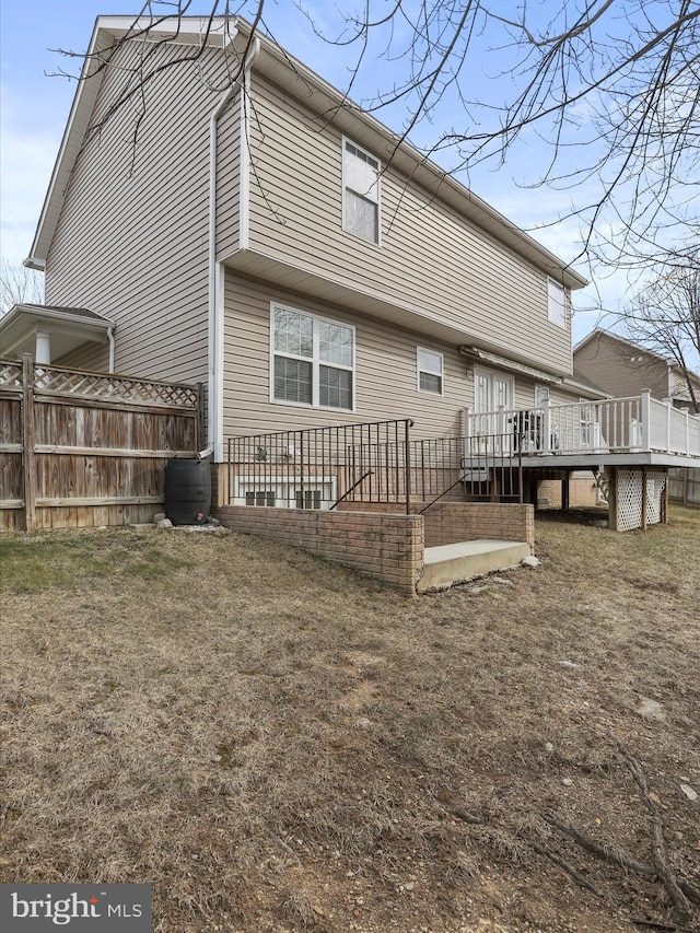 back of house featuring a yard, a wooden deck, and fence