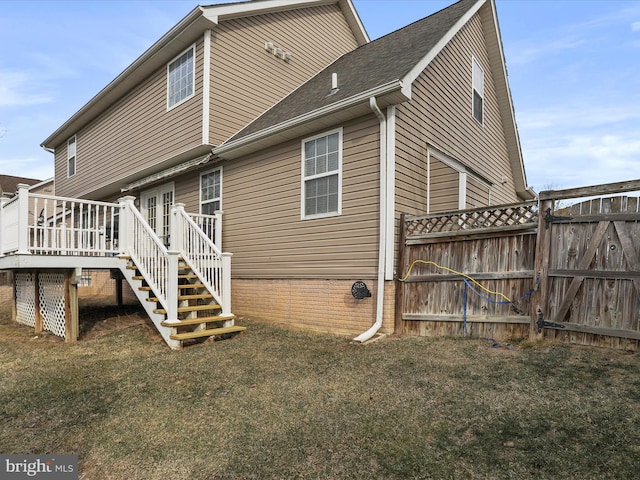 back of property featuring stairs, fence, a deck, and a lawn