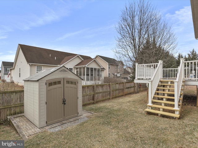 view of yard with a fenced backyard, an outdoor structure, stairway, a wooden deck, and a storage unit