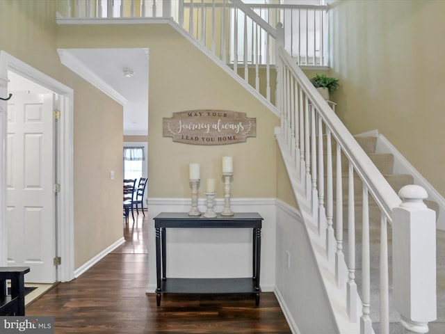 stairway featuring ornamental molding, wood finished floors, and a high ceiling