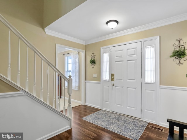 entrance foyer with visible vents, a wainscoted wall, stairway, ornamental molding, and dark wood-style flooring