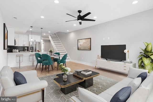 living room featuring recessed lighting, visible vents, baseboards, stairs, and light wood-style floors