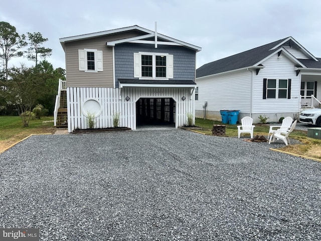 view of front facade with gravel driveway, an attached garage, and stairway