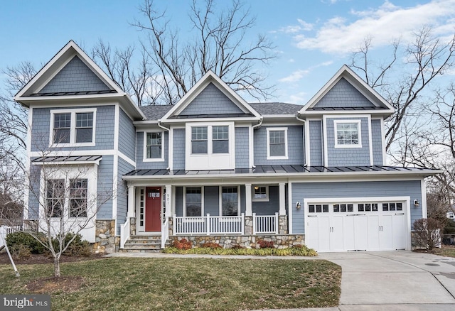 view of front of house featuring concrete driveway, a front yard, a standing seam roof, a garage, and stone siding