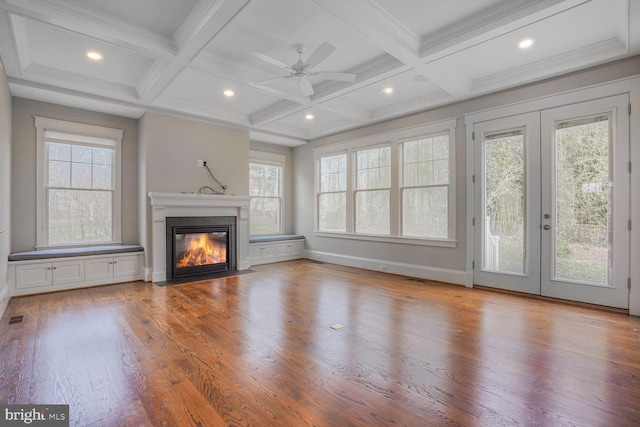 unfurnished living room featuring a fireplace with flush hearth, beam ceiling, coffered ceiling, and wood finished floors