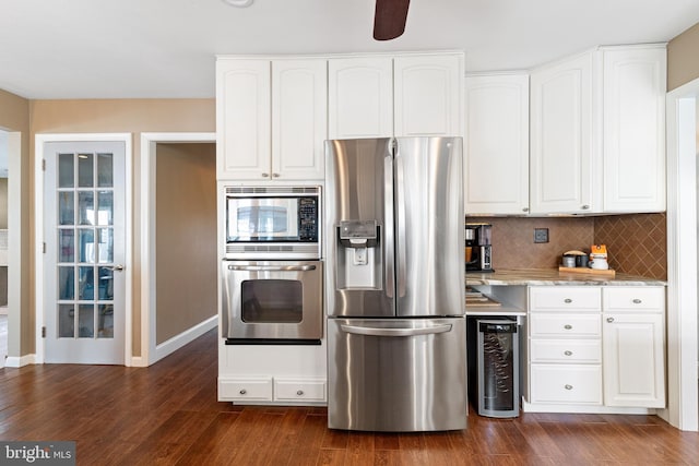 kitchen featuring dark wood-style floors, decorative backsplash, appliances with stainless steel finishes, white cabinetry, and light stone countertops