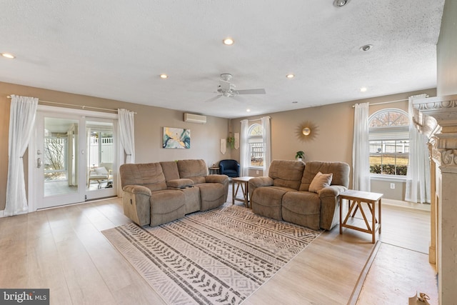 living area with a textured ceiling, a wall mounted air conditioner, wood finished floors, and recessed lighting