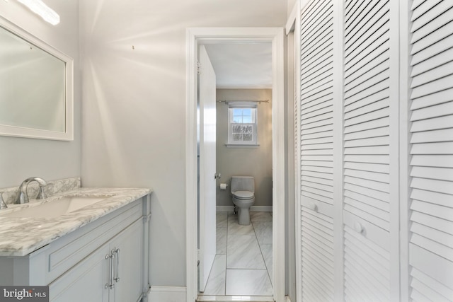 bathroom featuring toilet, baseboards, a closet, and vanity