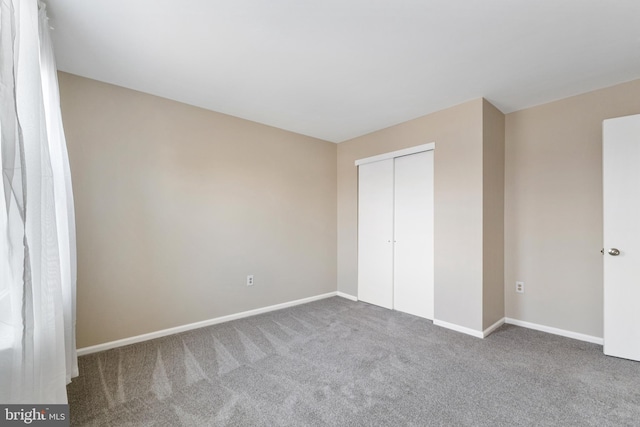 unfurnished bedroom featuring carpet floors, a closet, and baseboards