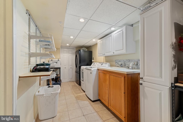 laundry room featuring light tile patterned floors, recessed lighting, cabinet space, washing machine and dryer, and a sink