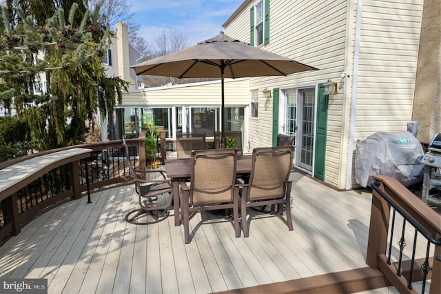 wooden terrace featuring a grill and outdoor dining area