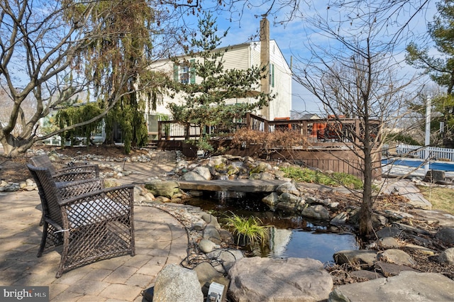 view of patio featuring a deck and a small pond