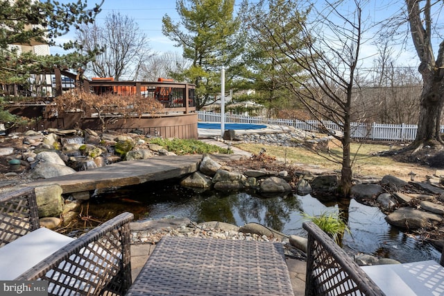 view of yard with a fenced in pool, a wooden deck, a garden pond, and fence