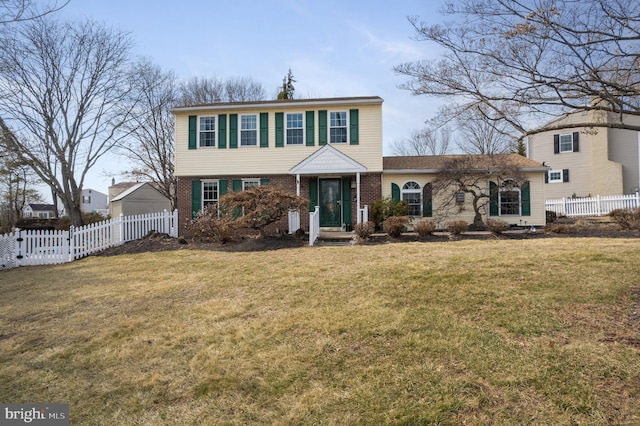 colonial inspired home featuring fence, a front lawn, and brick siding