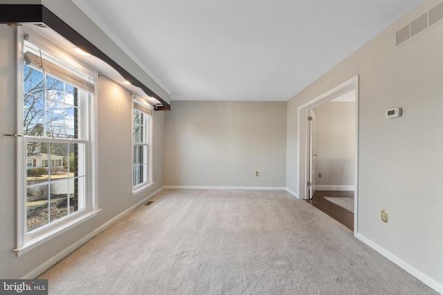 unfurnished room with carpet, visible vents, and baseboards