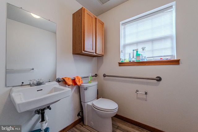 bathroom with toilet, baseboards, a sink, and wood finished floors