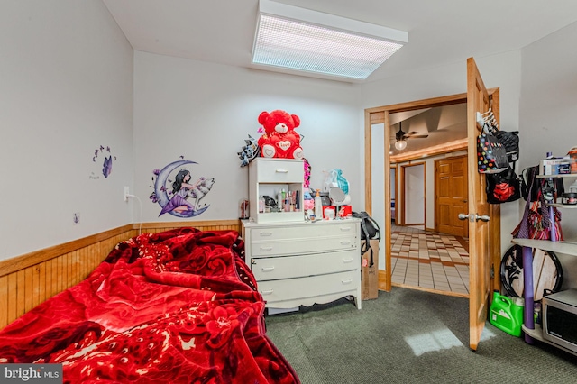 bedroom with carpet floors, wood walls, and wainscoting