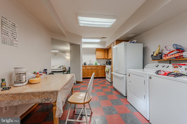 kitchen with dark floors, light countertops, a sink, white appliances, and independent washer and dryer